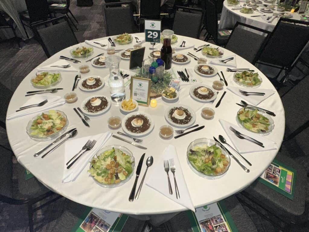 A round table set for ten with salads, plates, utensils, drinks, and a centerpiece at an event; table number 29 is displayed.