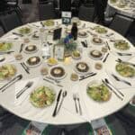 A round table set for ten with salads, plates, utensils, drinks, and a centerpiece at an event; table number 29 is displayed.
